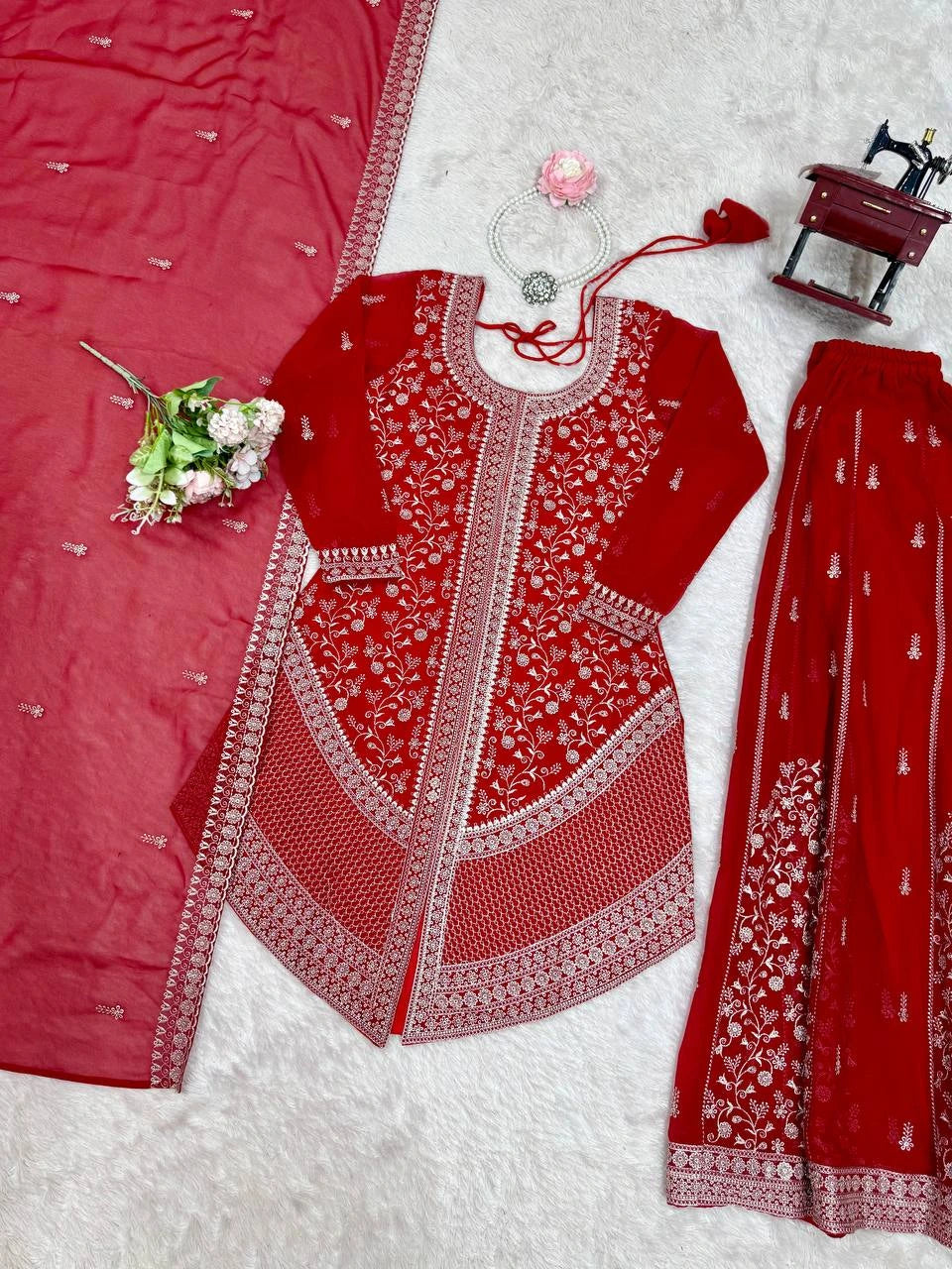 Red embroidered traditional outfit with white patterns on a white background