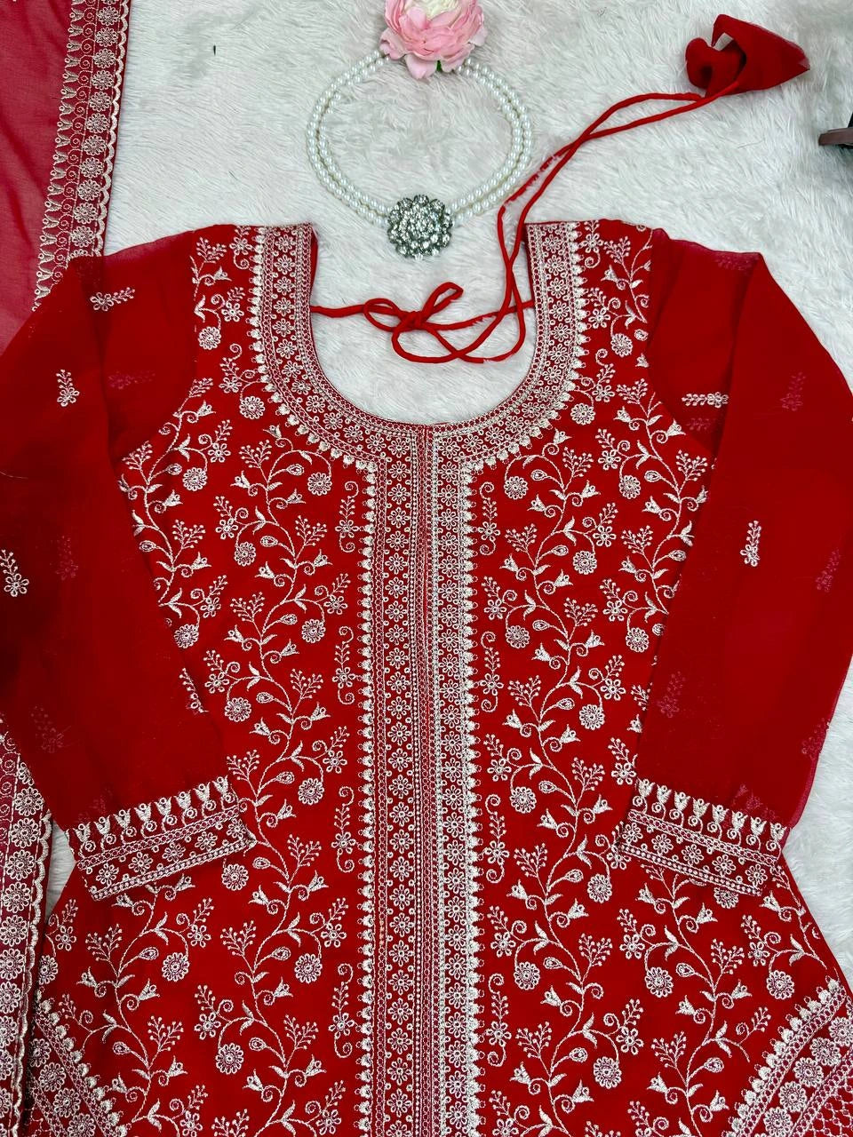 Red embroidered garment with white patterns on a light background