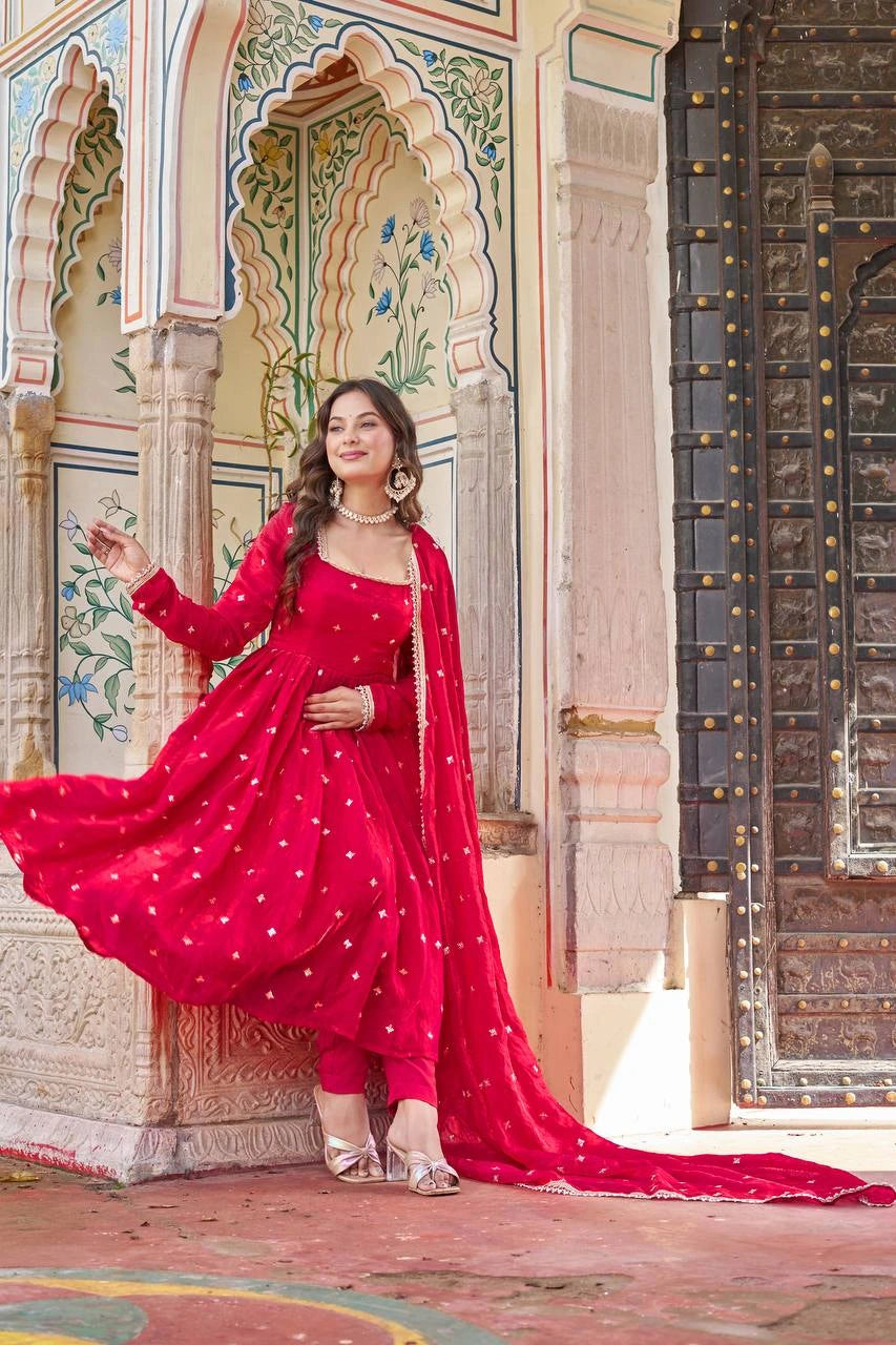 Woman in a red traditional outfit standing in front of an ornate architectural background