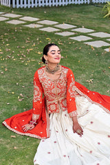 Woman in a red and white traditional outfit sitting on grass