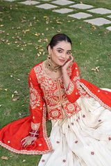 Woman in traditional red and white embroidered outfit sitting on grass