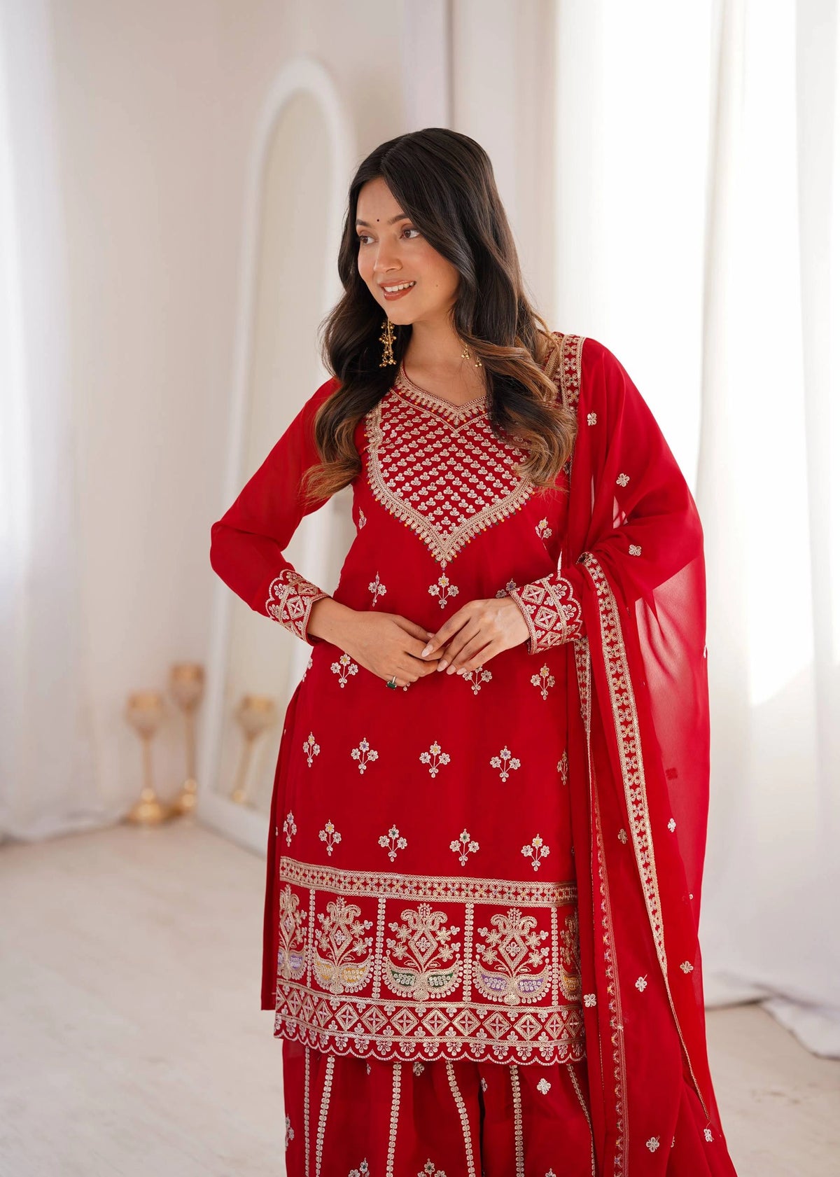 Woman wearing a red embroidered traditional outfit with a white background