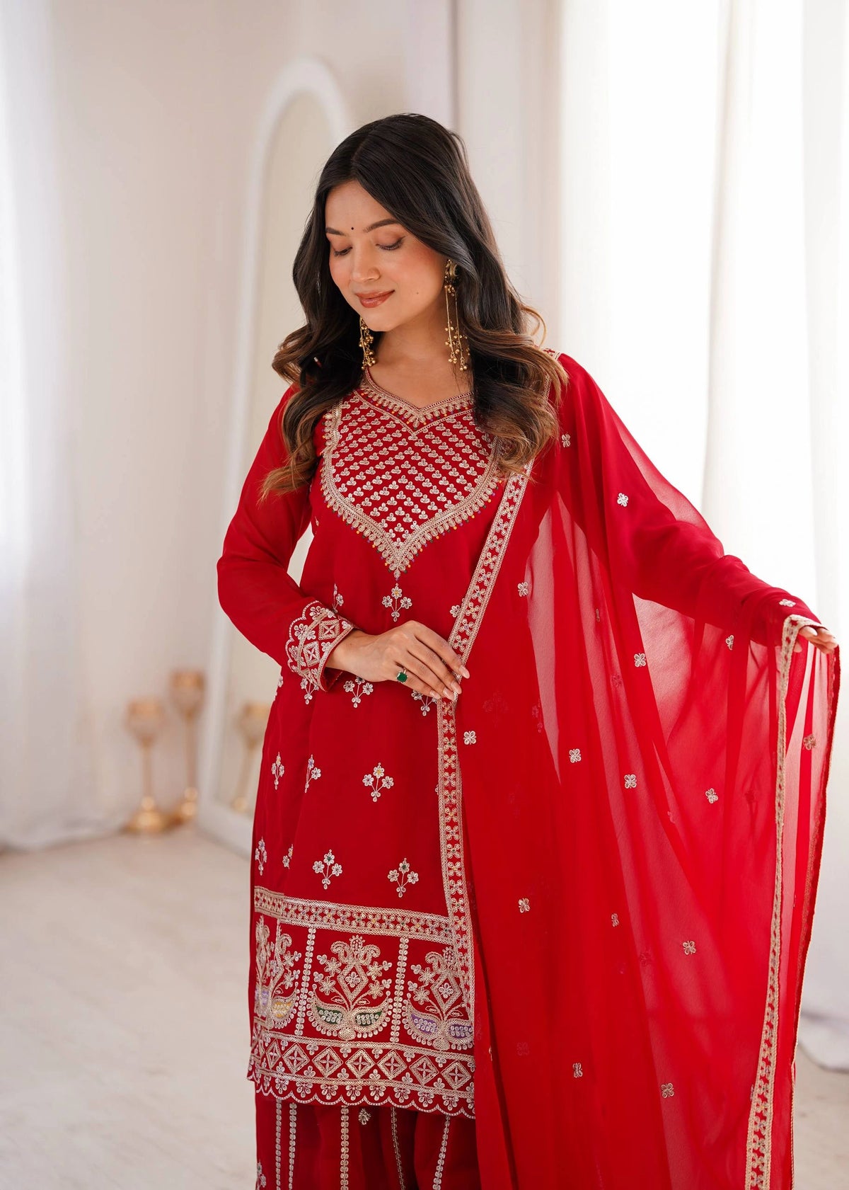 Woman wearing a red embroidered traditional outfit with a white background