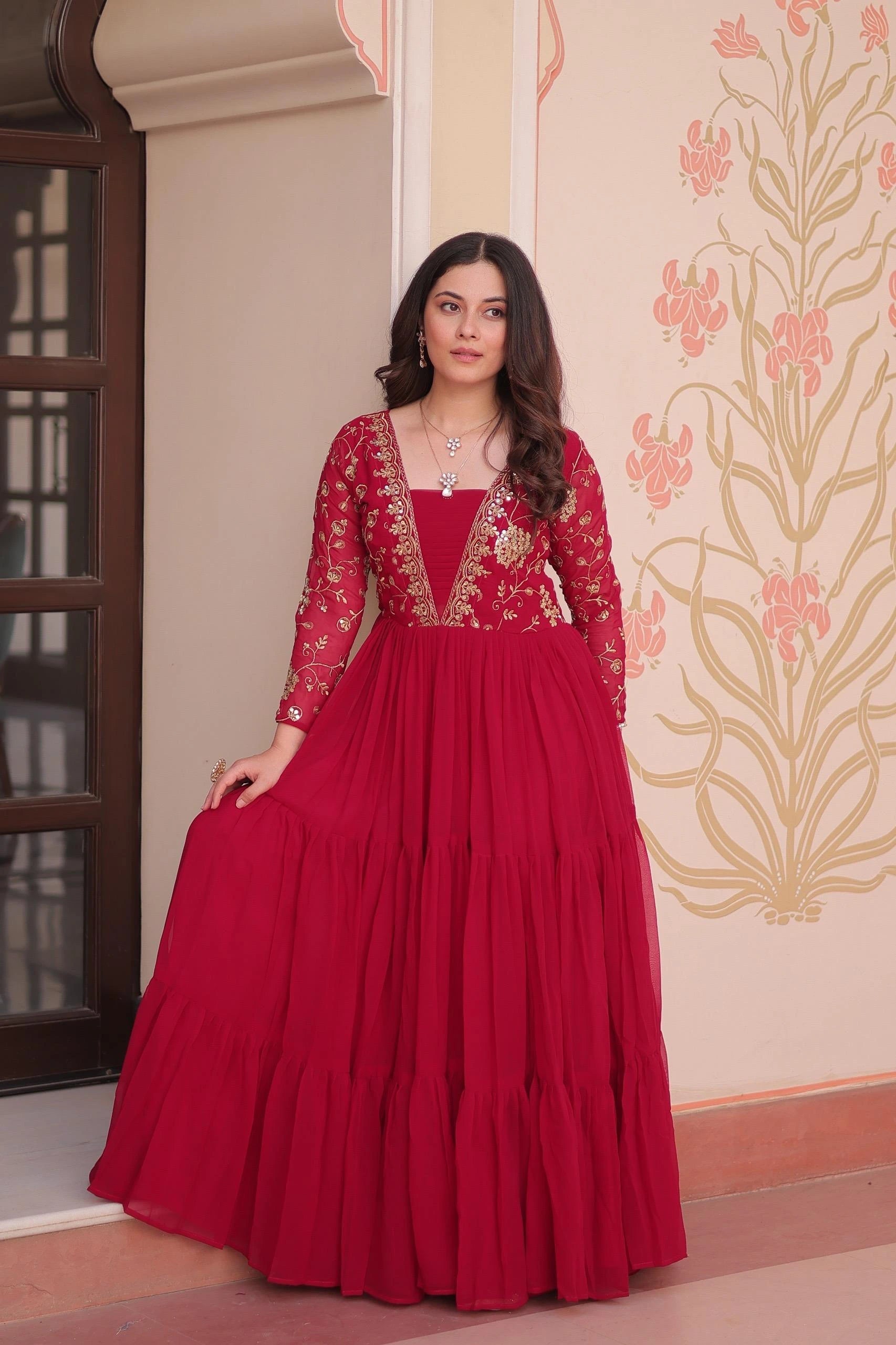 Woman wearing a red traditional outfit with intricate designs indoors.