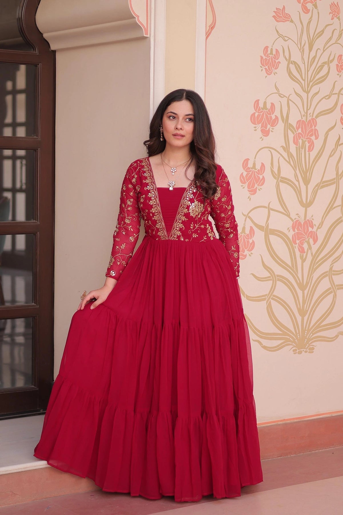 Woman wearing a red traditional outfit with intricate designs indoors.