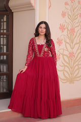Woman wearing a red traditional outfit with intricate designs indoors.