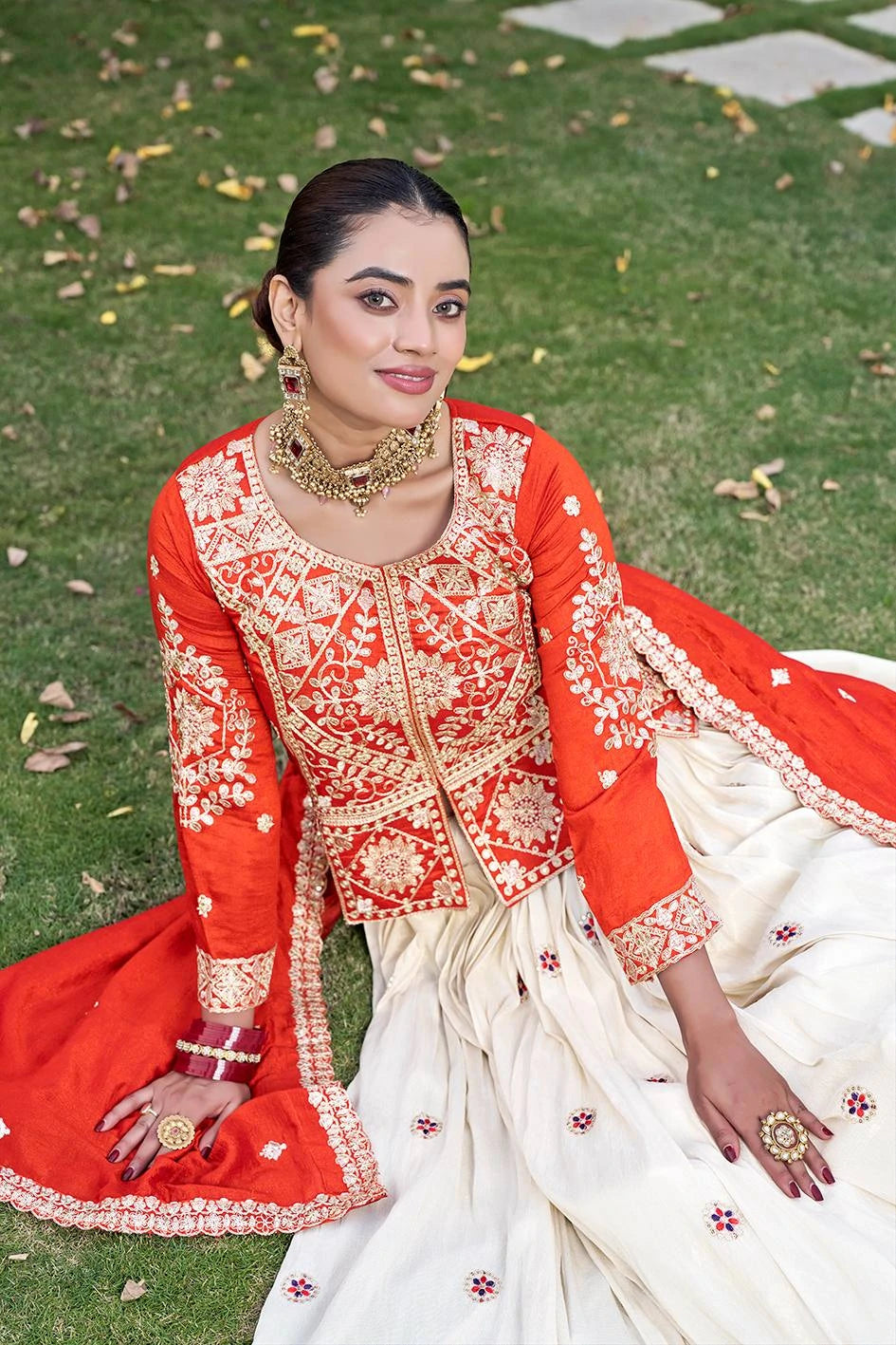 Woman in traditional red and white embroidered outfit sitting on grass