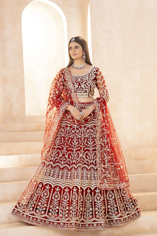 Woman wearing a red and gold embroidered traditional outfit in an elegant setting.