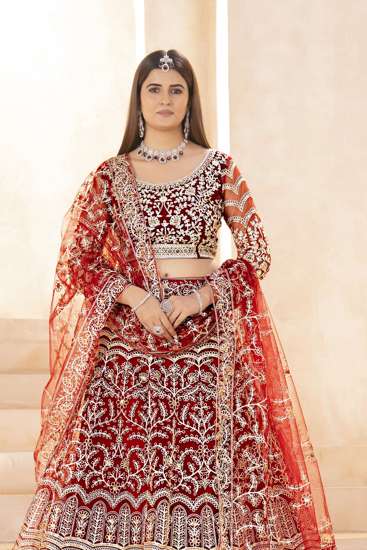 Woman wearing a red and white embroidered traditional outfit with a matching dupatta.