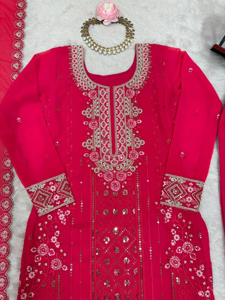 Red embroidered traditional outfit with jewelry on a light gray background