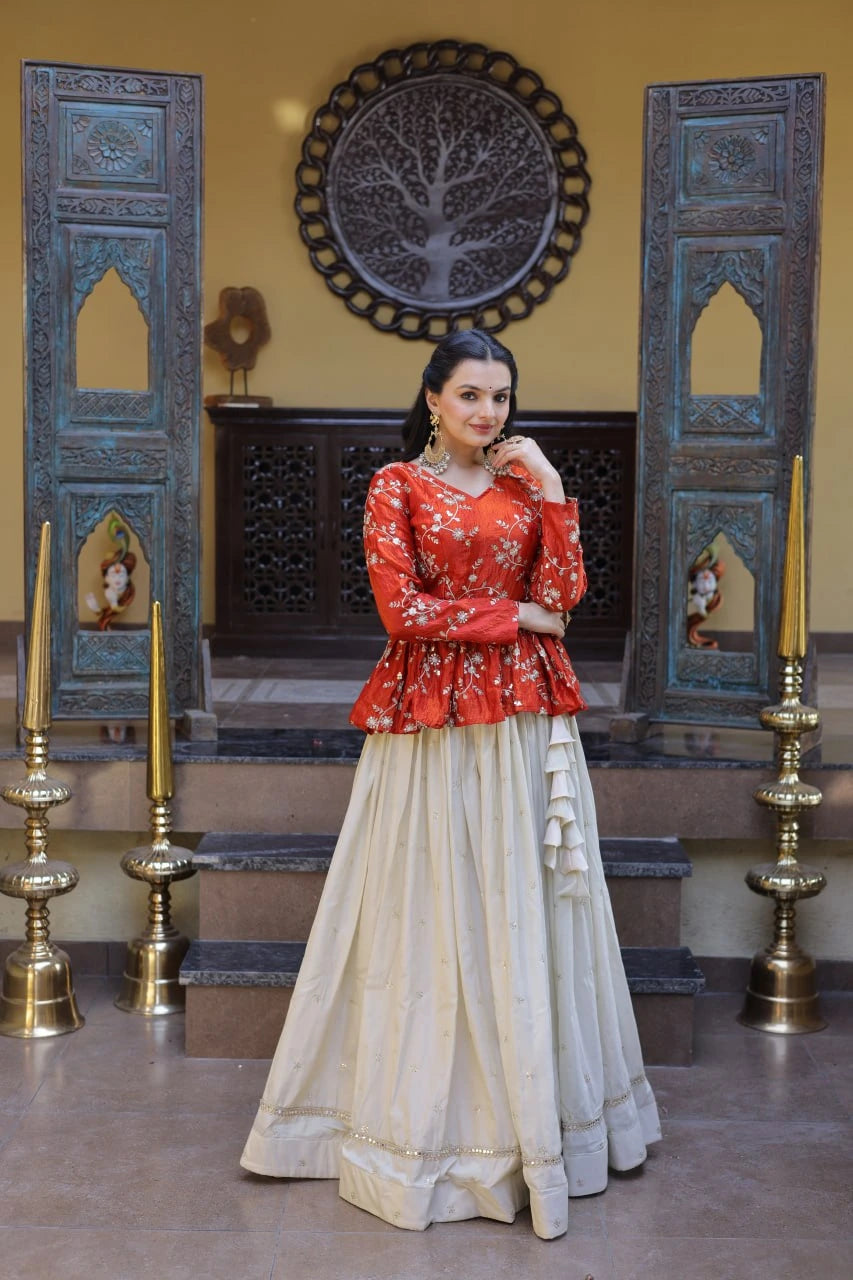 Woman in a red top and beige skirt standing in a decorated room with blue wooden panels and gold candle holders.