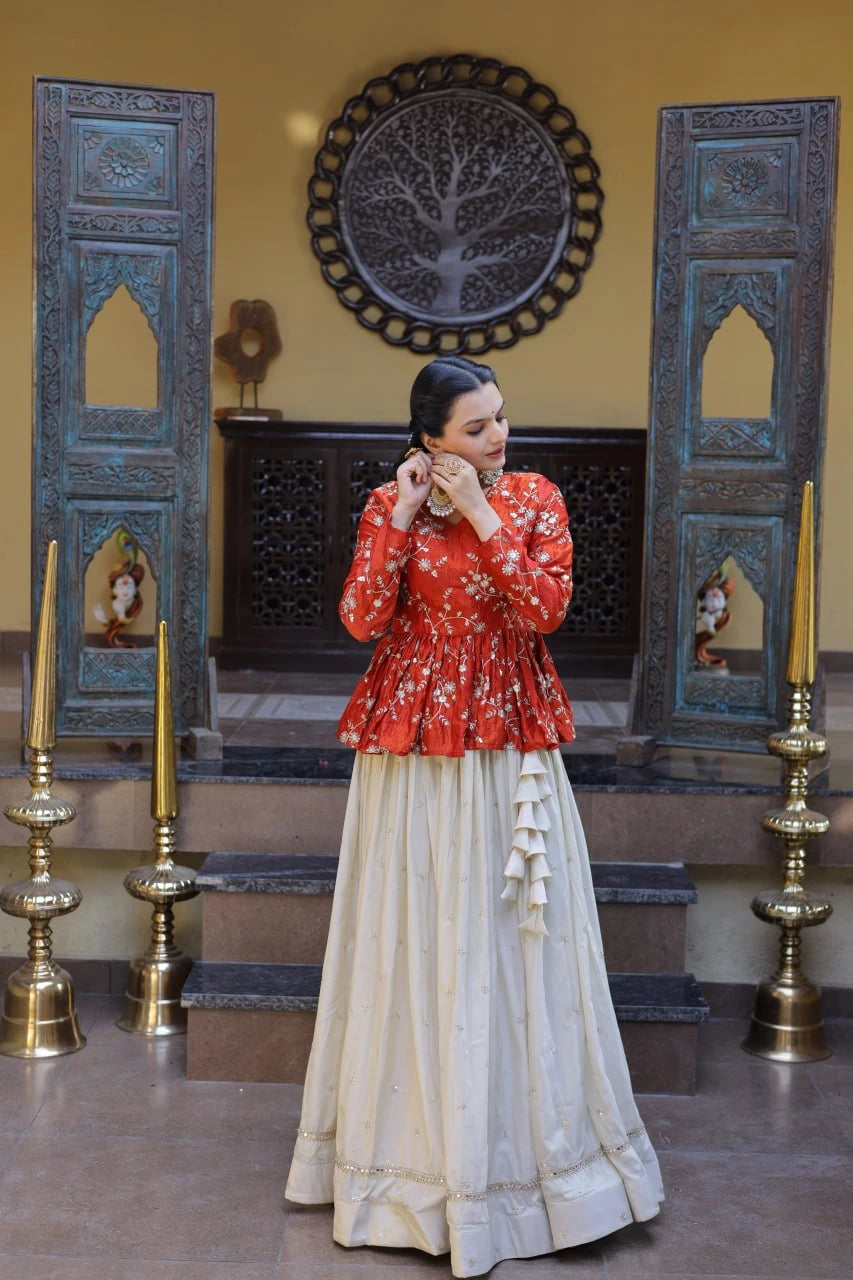 Woman in a red top and white skirt standing in a decorated room with blue wooden panels and gold candle holders.