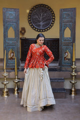Woman in a red top and beige skirt standing in a decorated room with blue wooden panels and gold candle holders.