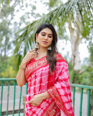 Woman in a red and white saree standing outdoors with greenery in the background