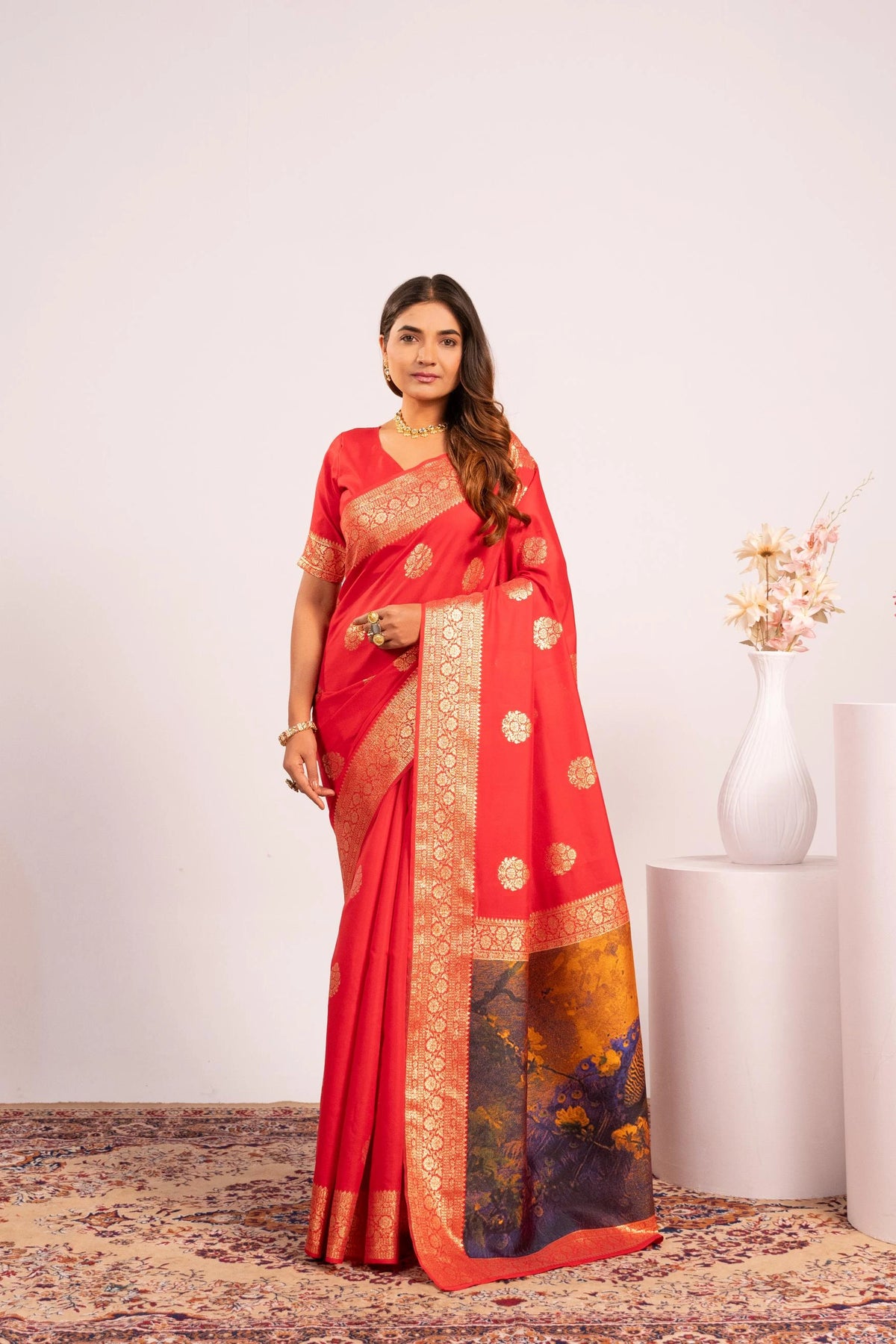 Woman wearing a red saree with gold and black patterns on a white background