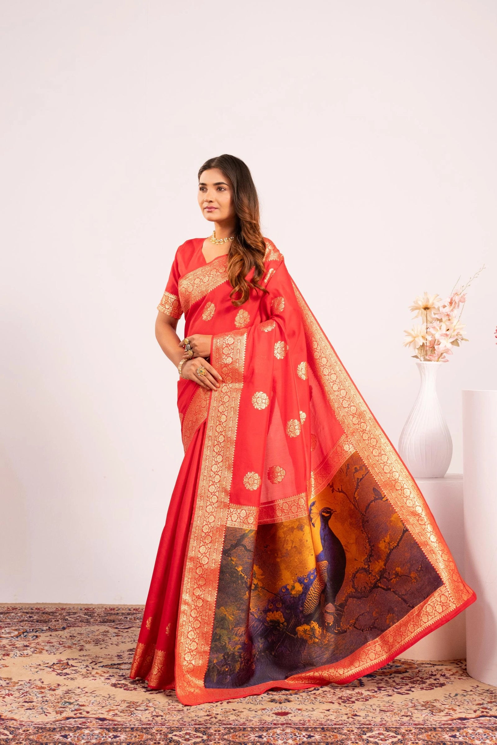 Woman wearing a red saree with gold patterns on a white background