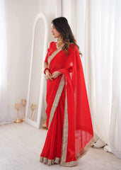 Woman wearing a red saree with gold border in a bright room.