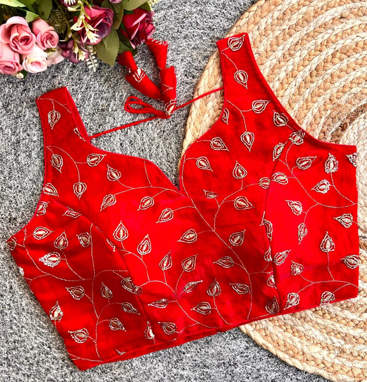 Red patterned top on a textured surface with flowers in the corner