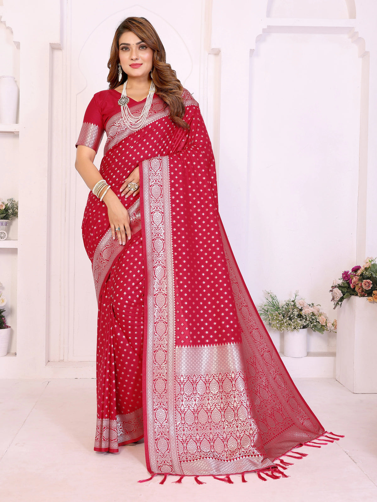 Woman wearing a red saree with white patterns in a bright room.
