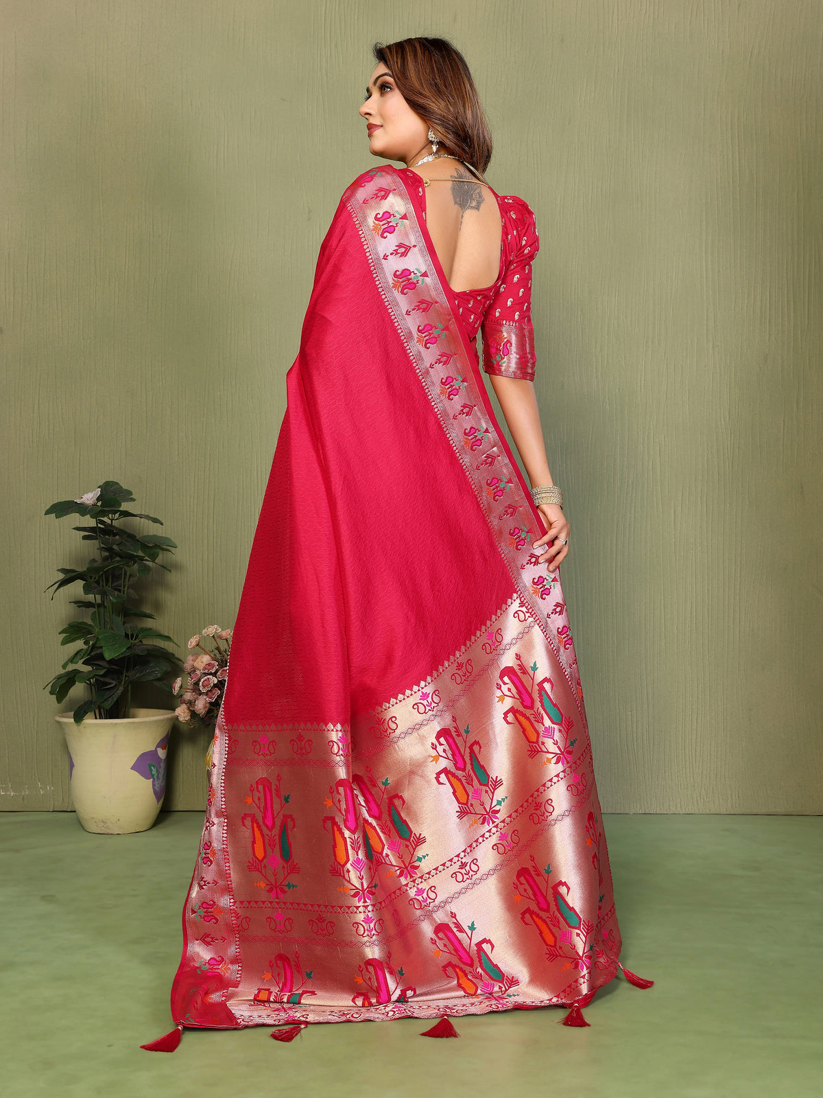 Woman wearing a pink saree with intricate patterns on a green background