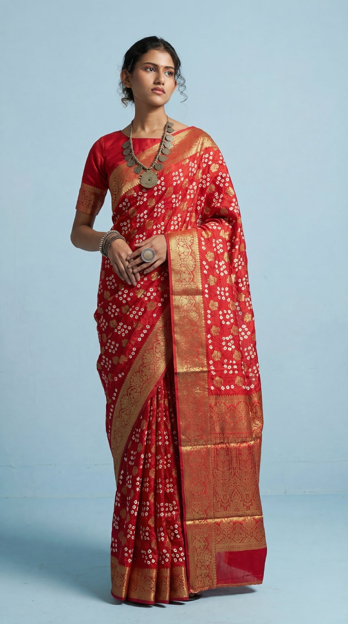 Woman wearing a red saree with gold border on a light blue background