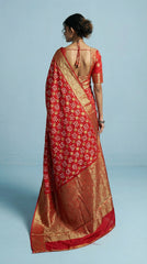 Woman wearing a red saree with white patterns on a light blue background