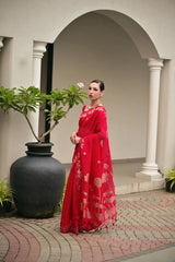Woman in a red dress standing in an outdoor setting with columns and plants.