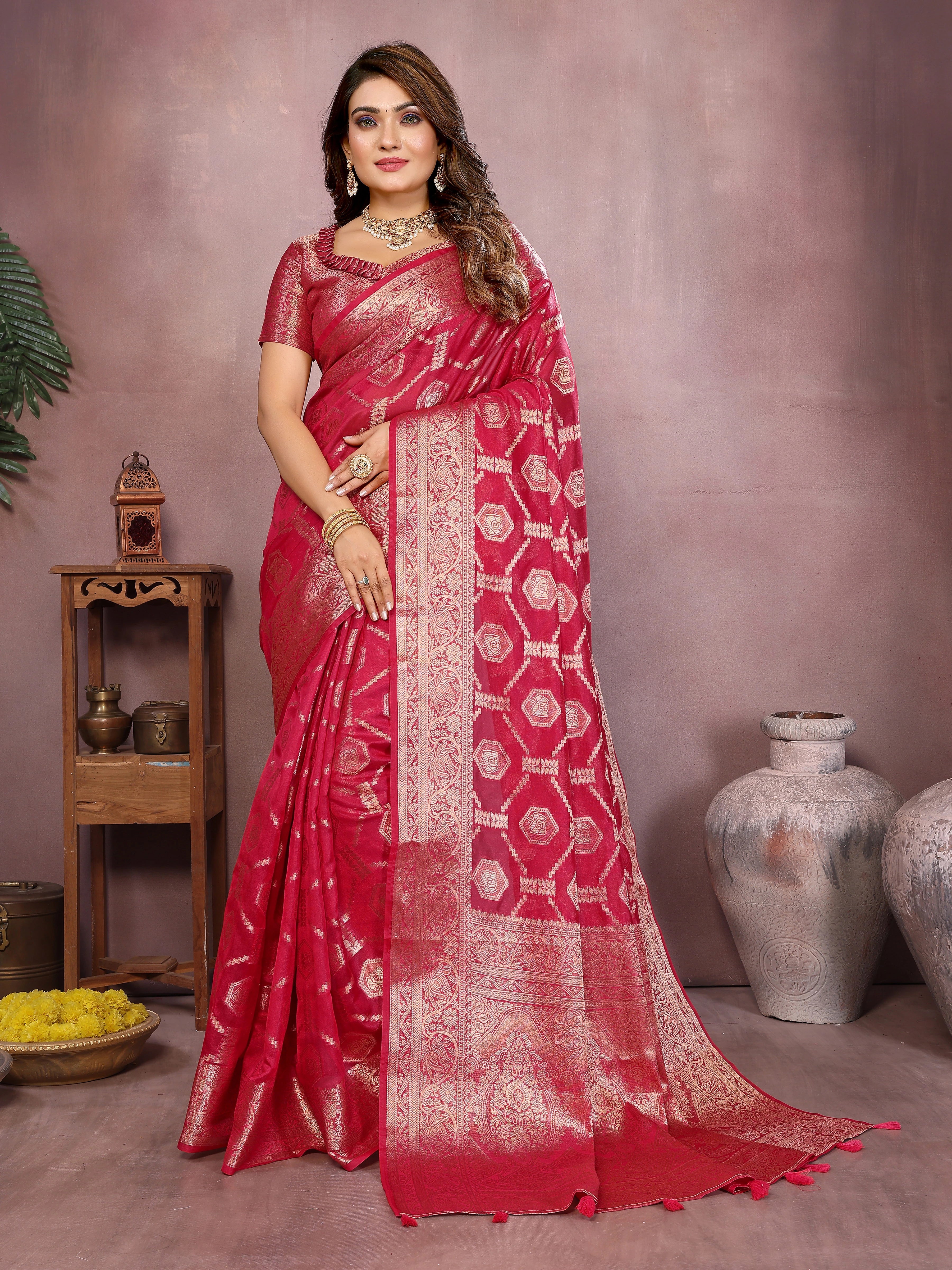 Woman wearing a red saree with white patterns in a decorative setting.