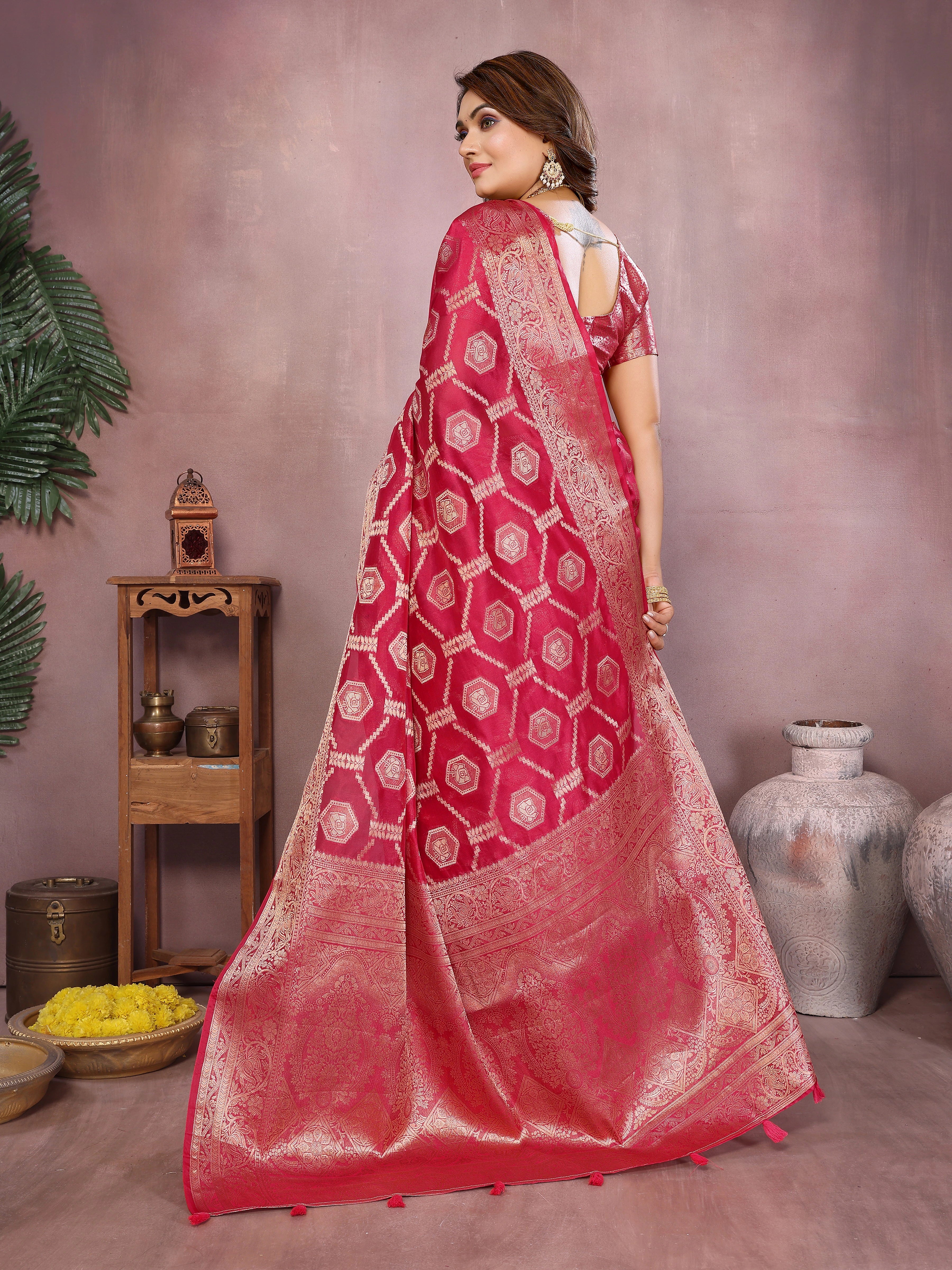 Woman wearing a red saree with white patterns in a room setting.