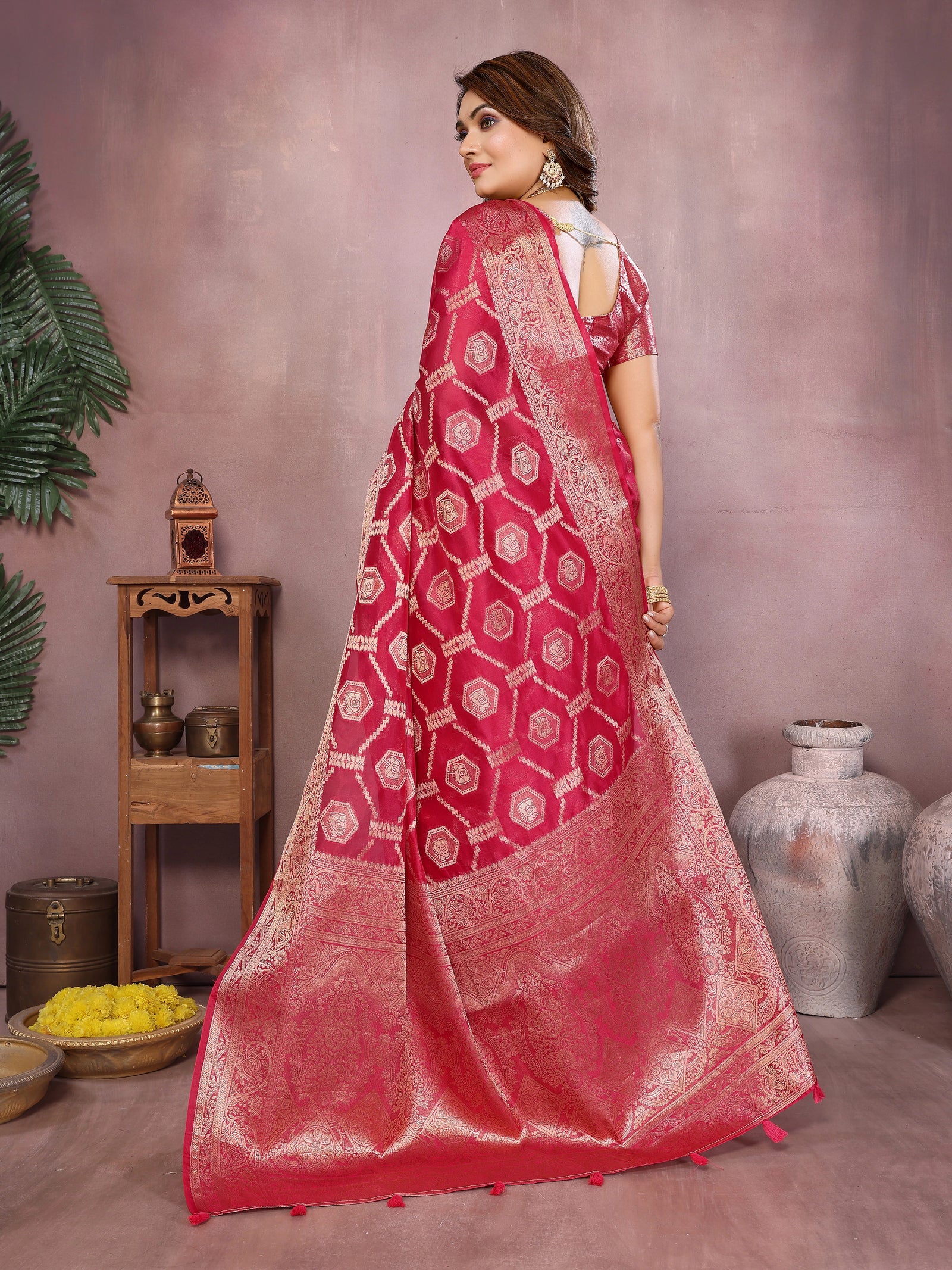 Woman wearing a red saree with white patterns in a room setting.