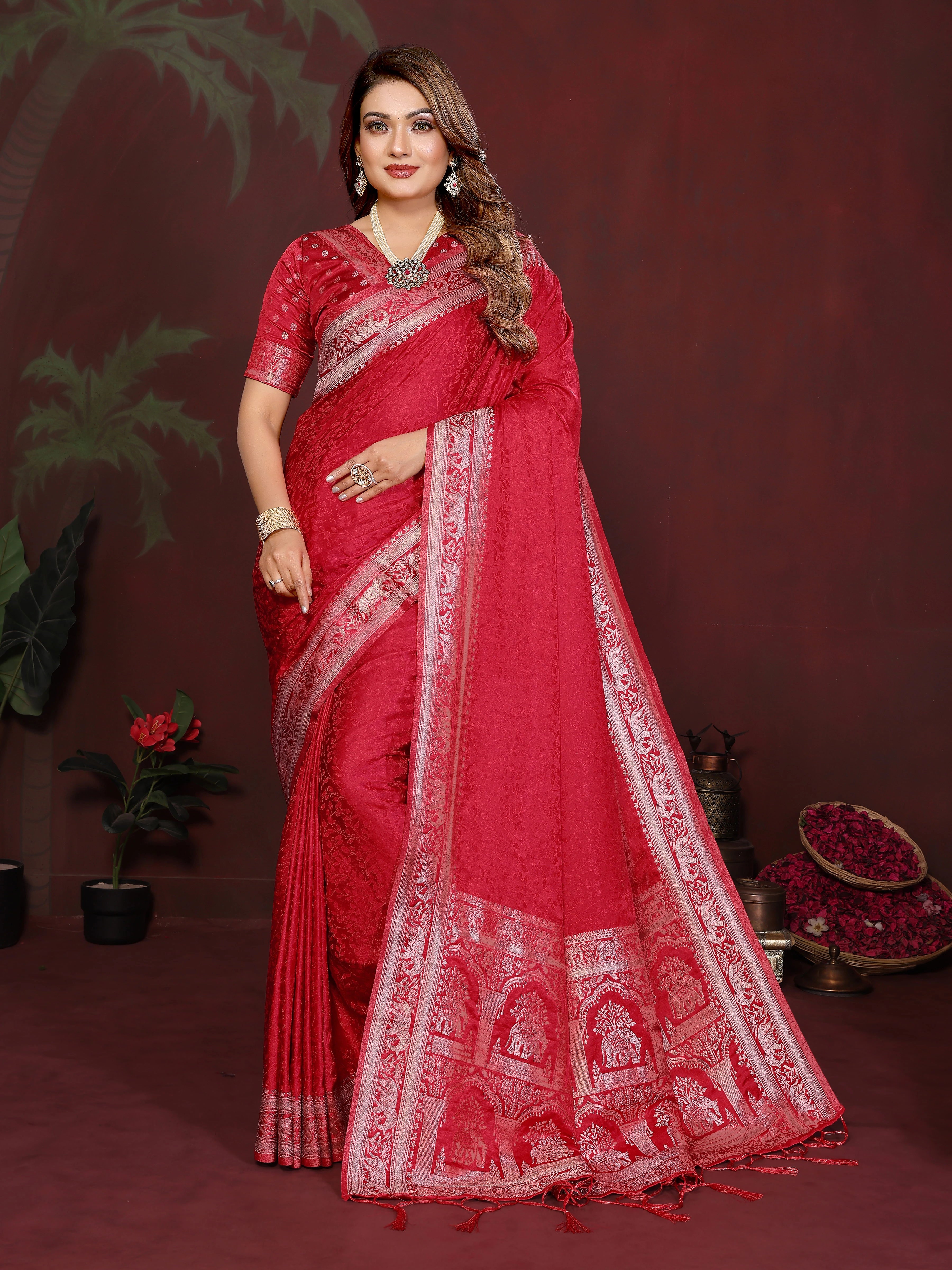 Woman wearing a red saree with white patterns against a dark background