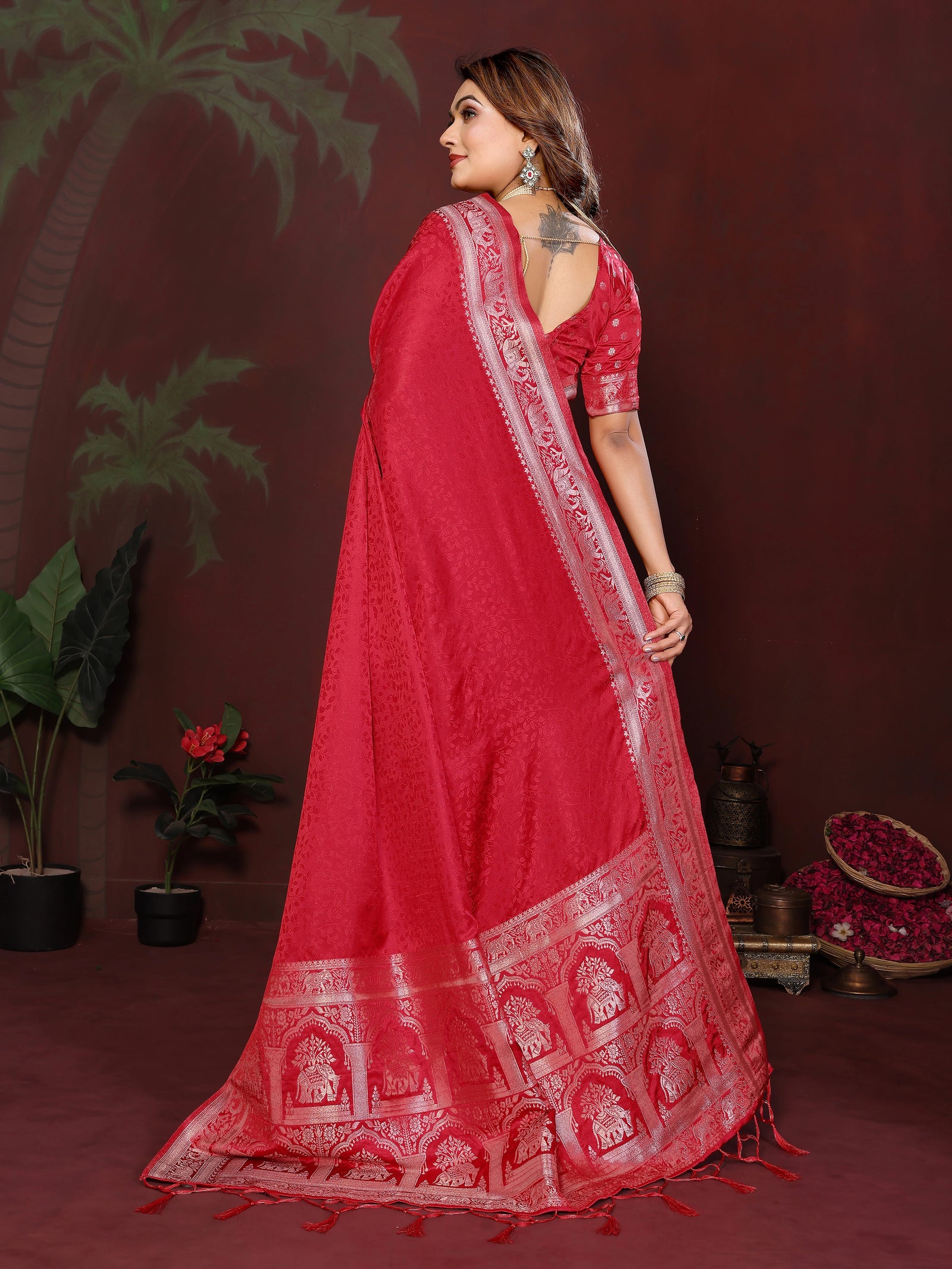 Woman wearing a red saree with intricate patterns against a dark background