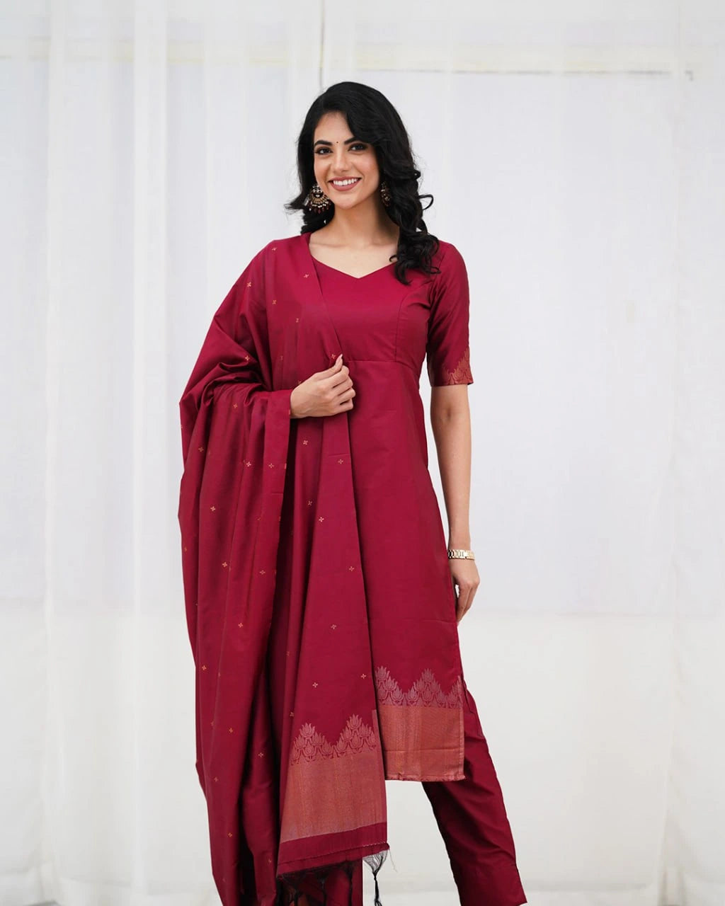 Woman wearing a maroon traditional outfit with a white background