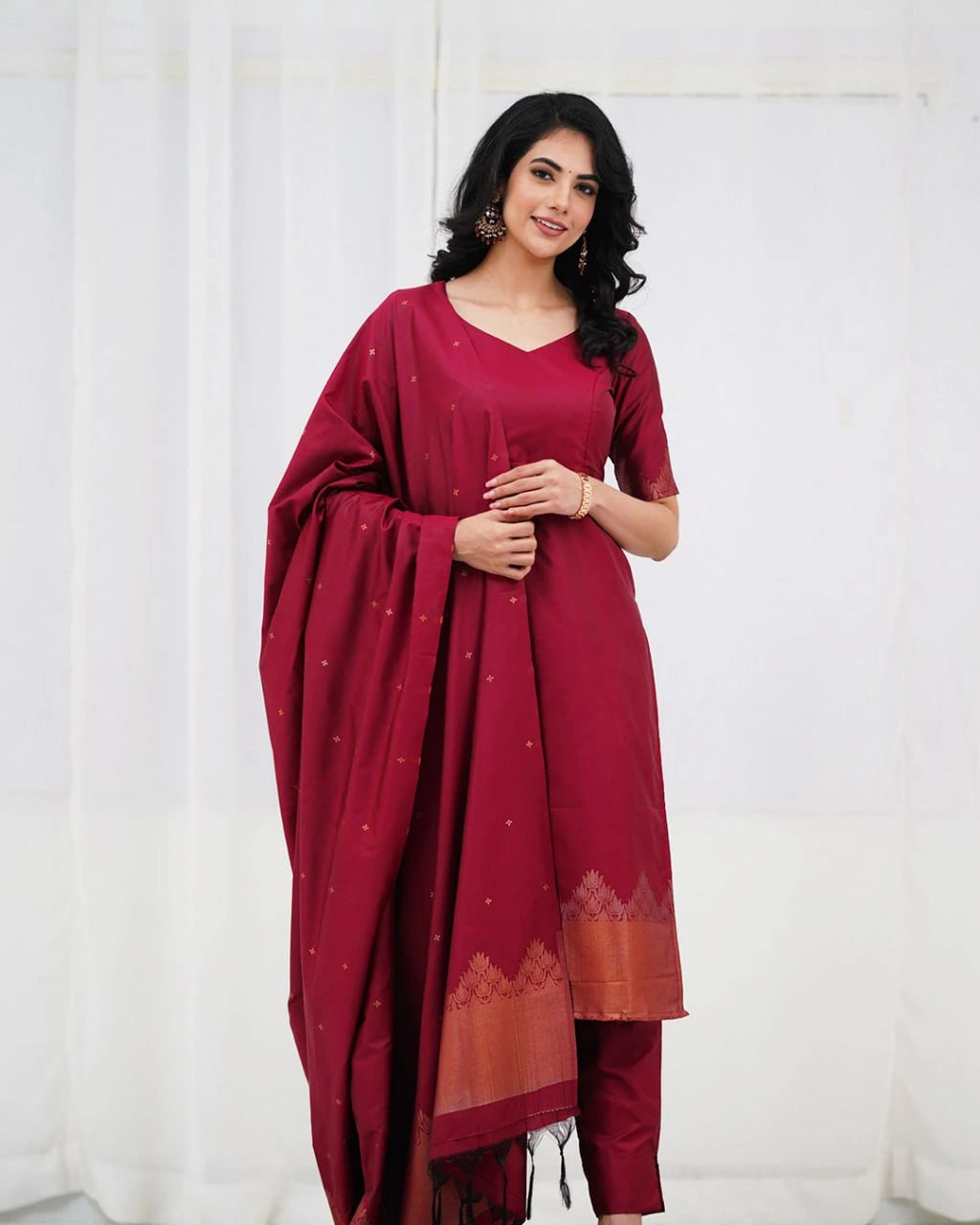 Woman wearing a maroon traditional outfit with a white background