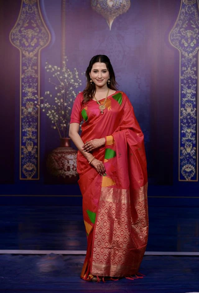 Woman in a red saree with green and yellow patterns against a decorative blue background