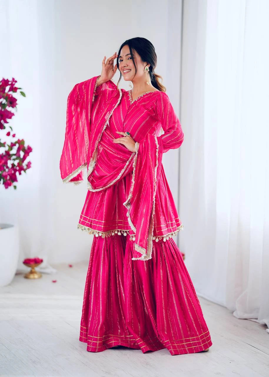 Woman wearing a bright pink traditional outfit with a matching dupatta against a white background
