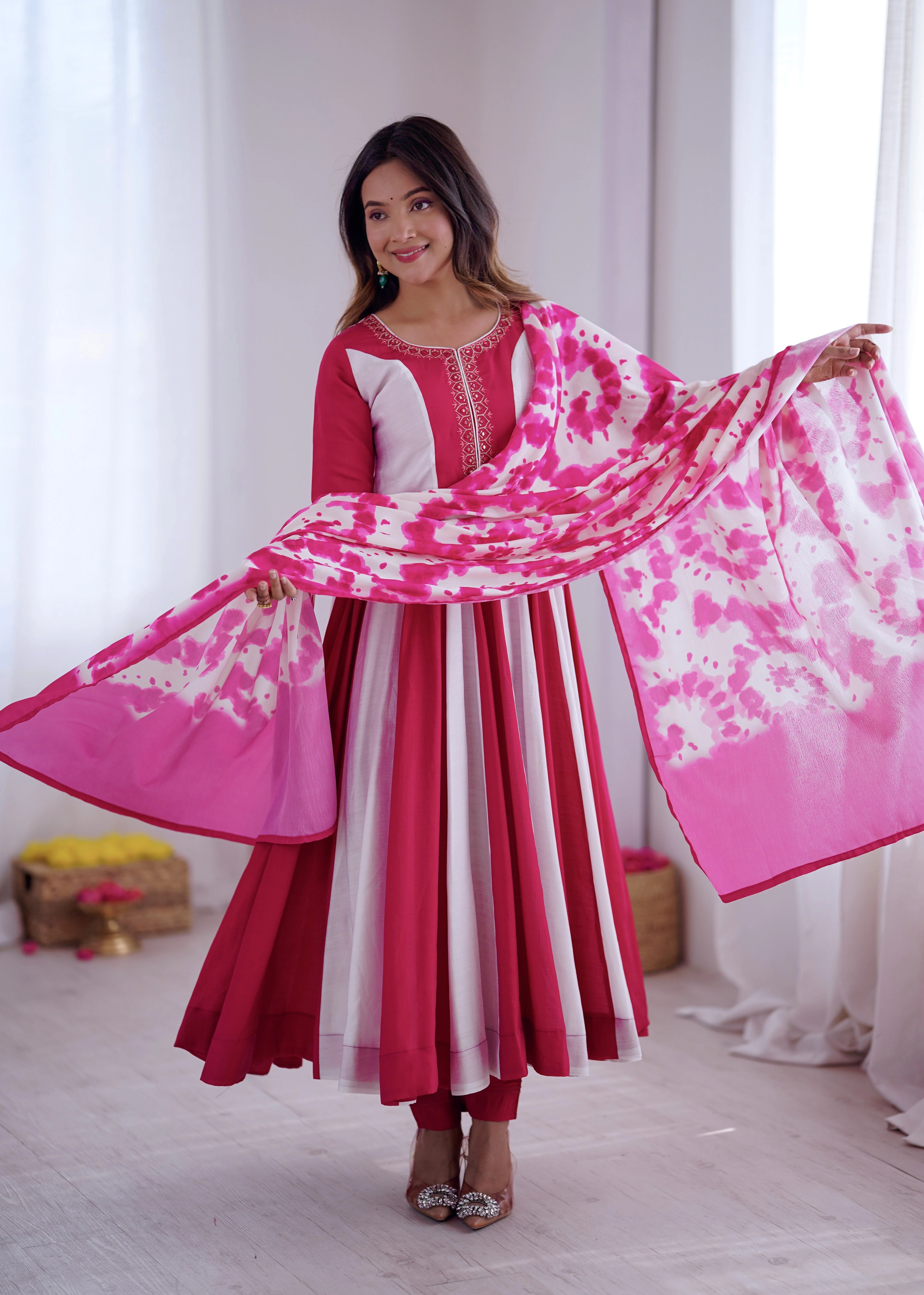 Woman in a red and white traditional outfit holding a pink and white scarf.