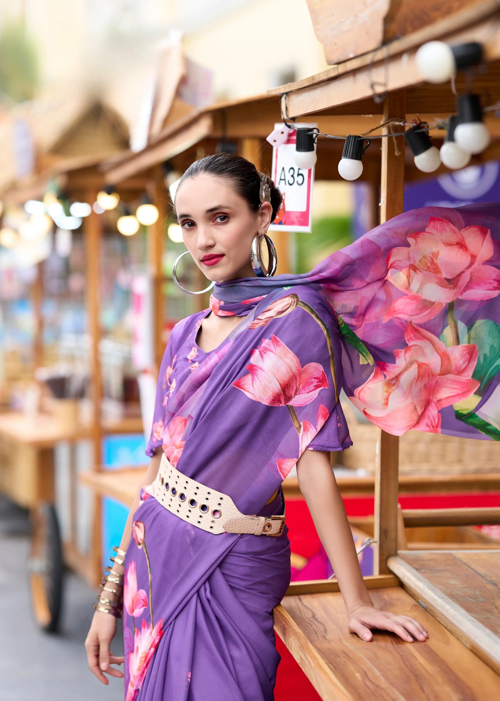 Woman in a purple floral sari with a blurred market background