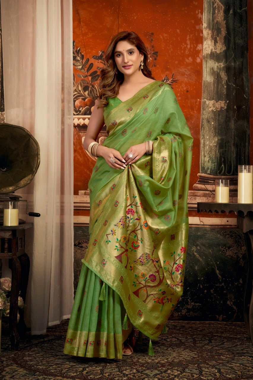 Woman wearing a green saree with floral patterns in an indoor setting.