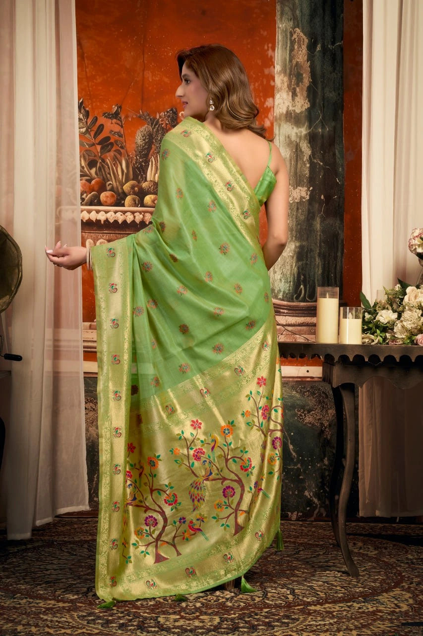 Woman wearing a green saree with floral patterns in an indoor setting.