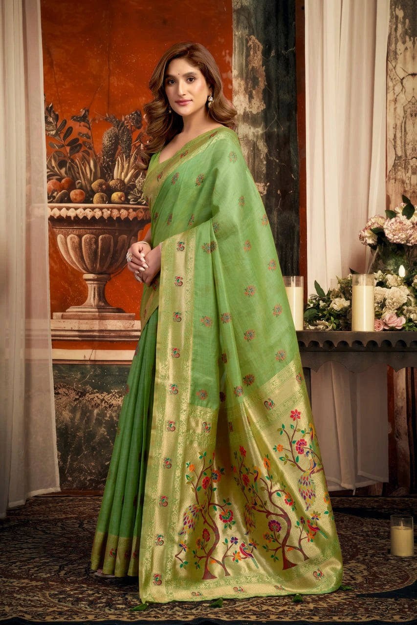 Woman wearing a green saree with floral patterns in an elegant indoor setting.
