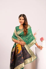 Woman wearing a green saree with a black and gold border, standing against a white background.