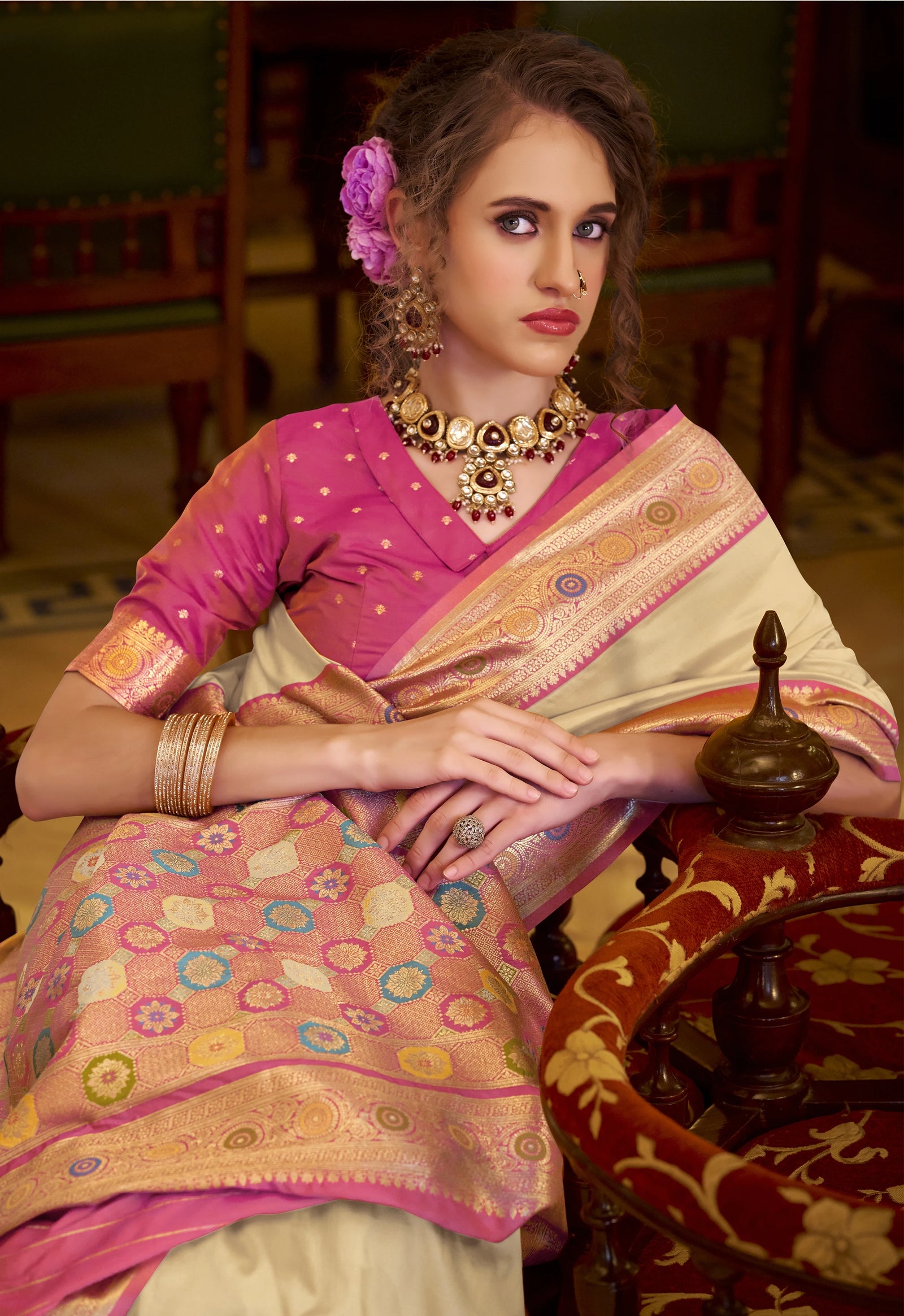 Woman in a traditional saree standing in an ornate room with decorative elements.