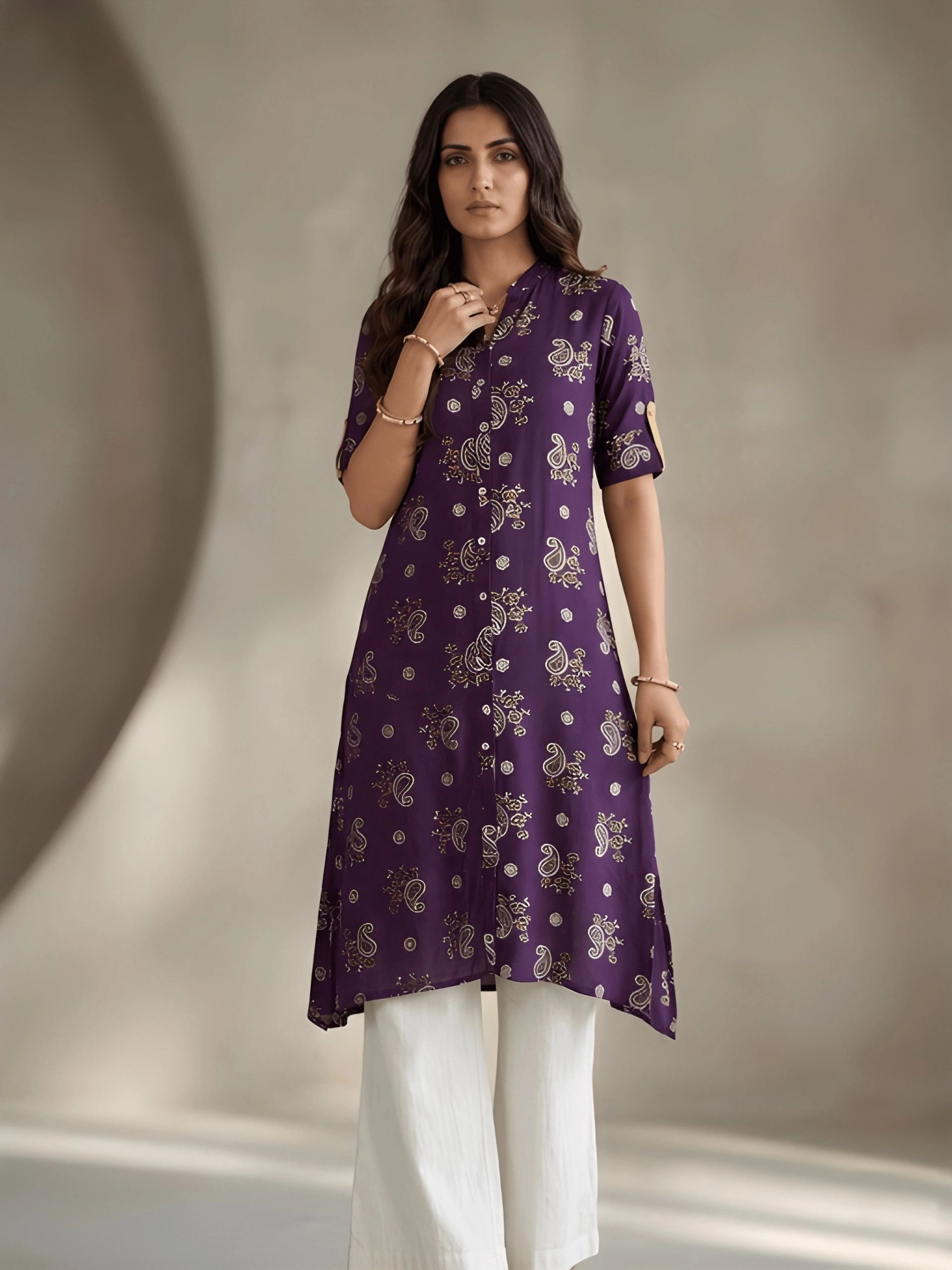 Woman wearing a purple patterned kurta with white pants against a neutral background