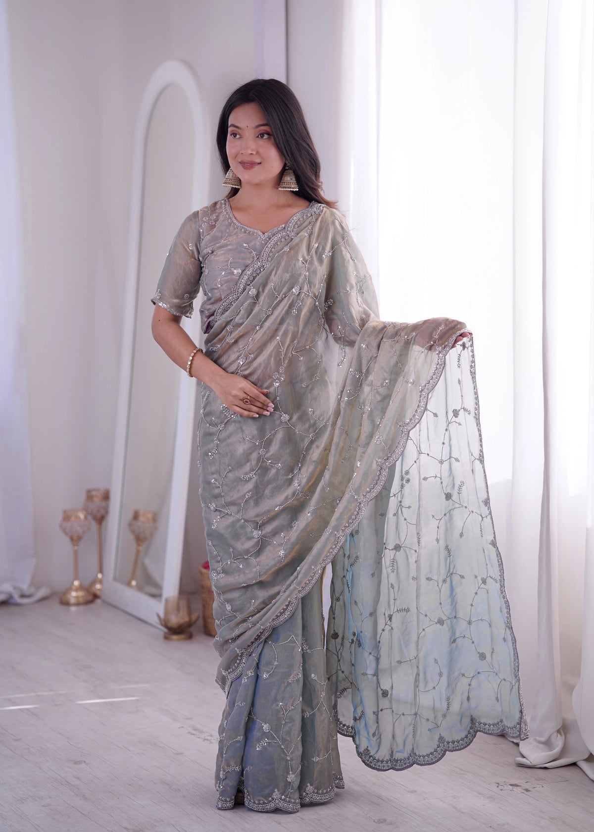 Woman wearing a silver saree with a white background