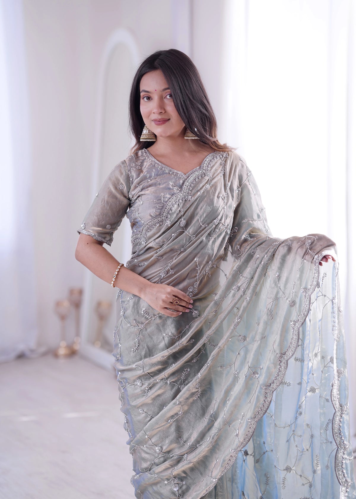 Woman wearing a light gray saree with a white background
