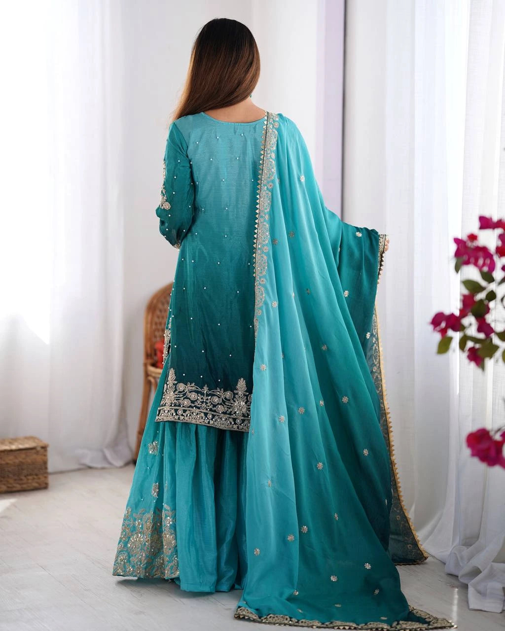 Teal traditional outfit with silver embroidery on a white background