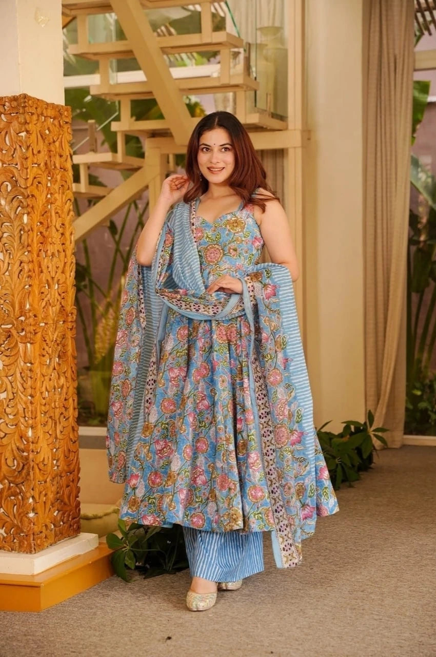 Woman in a floral traditional outfit standing indoors with decorative elements.