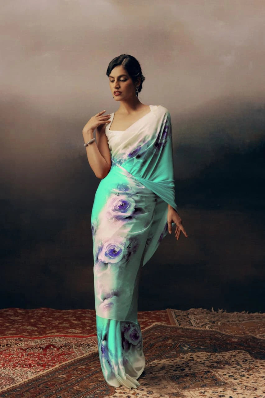 Woman wearing a light blue saree with floral patterns against a dark background
