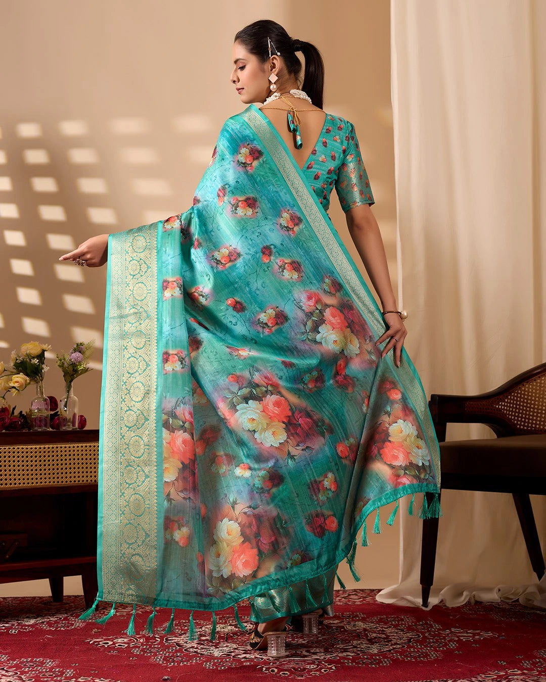 Woman wearing a floral saree with a decorative border indoors.